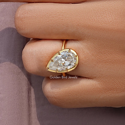Pear-cut solitaire ring viewed from the side, gold-tone setting with prongs