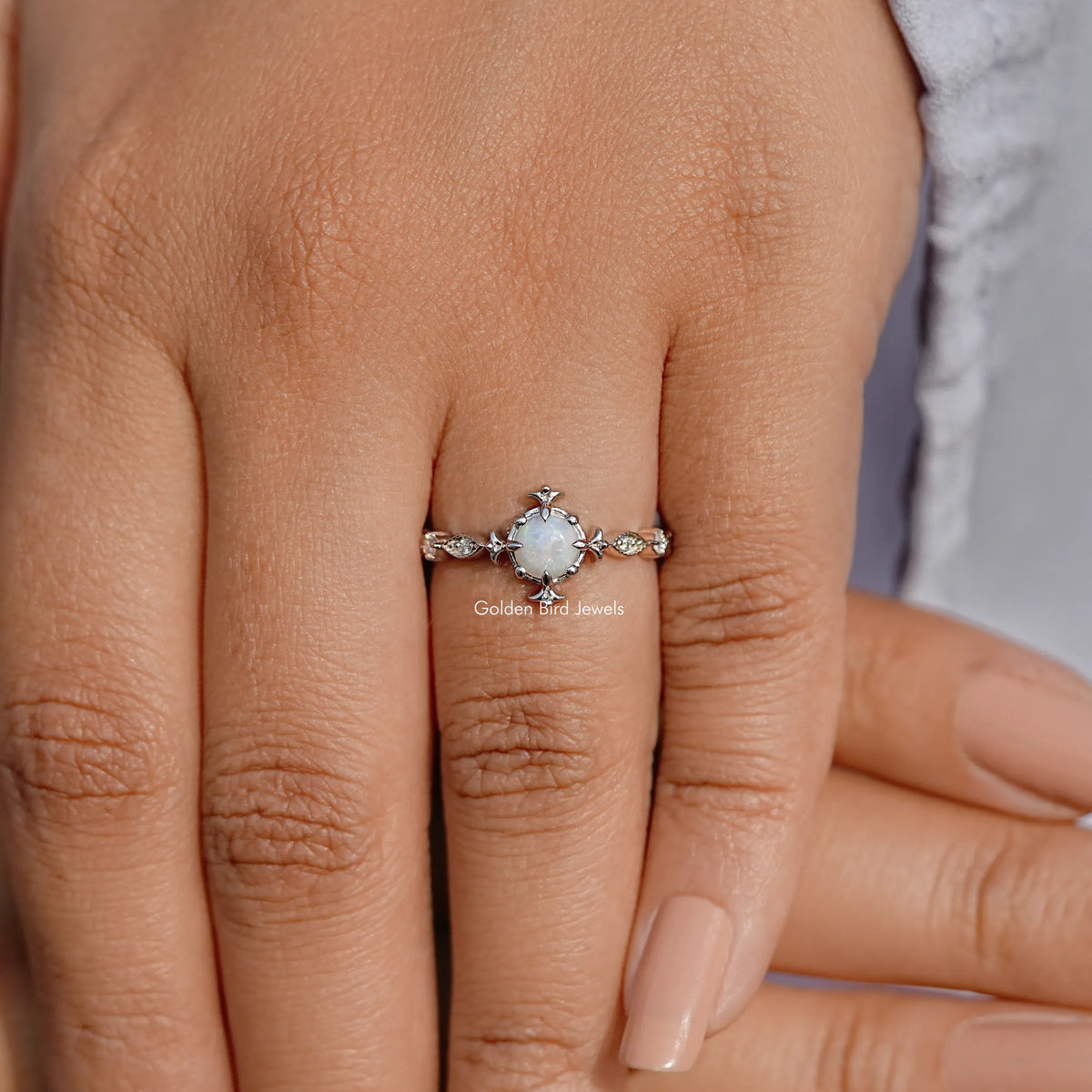 Opal round gemstone accent engagement ring on a hand