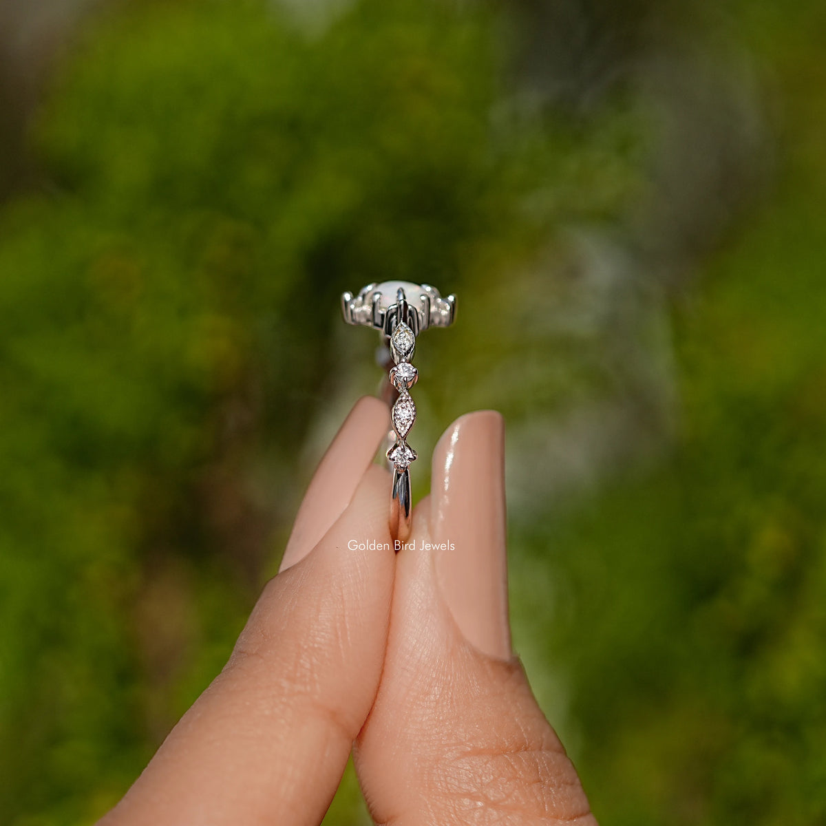 Silver-tone opal engagement ring with raised center and side sparkle stones, shown from side