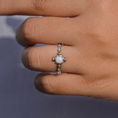 Opal halo engagement ring with prong setting and side stone details, worn on fingertip