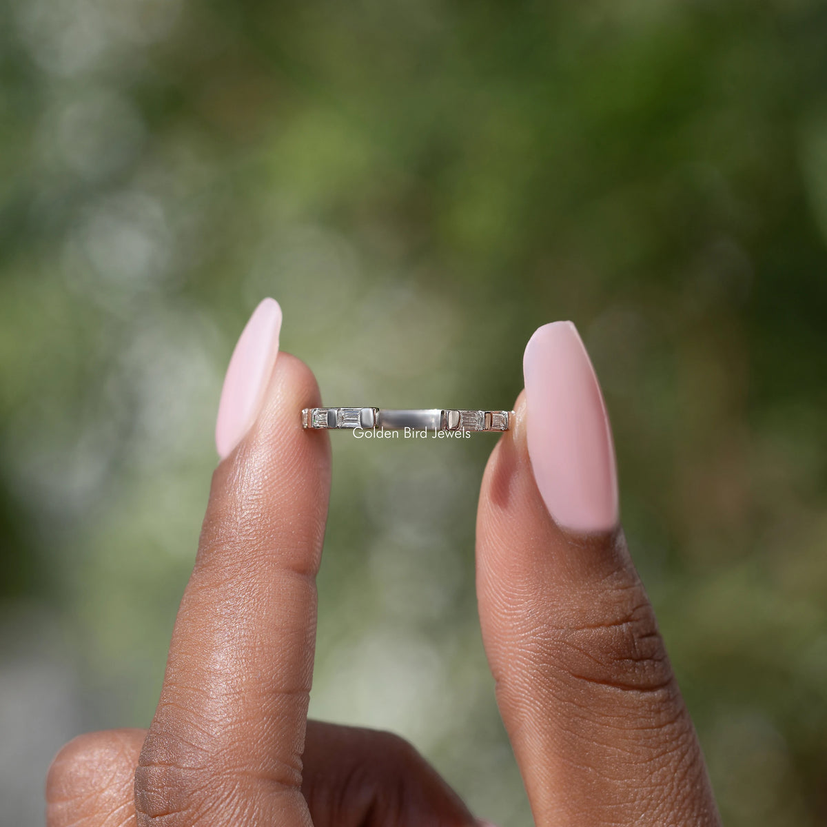 Silver baguette moissanite open-gap band between hands, bar-set stones