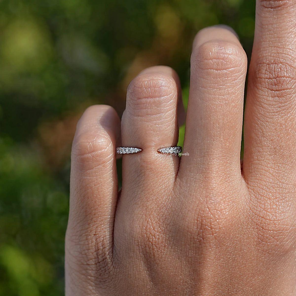 Silver open cuff ring with small round clear stones on a fingertip