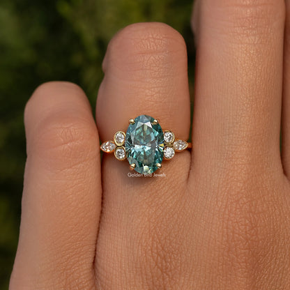 Oval blue-green moissanite proposal ring with round side stones, gold-tone setting