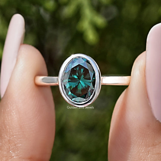 Front view of teal oval moissanite solitaire ring, bezel-set in sterling silver