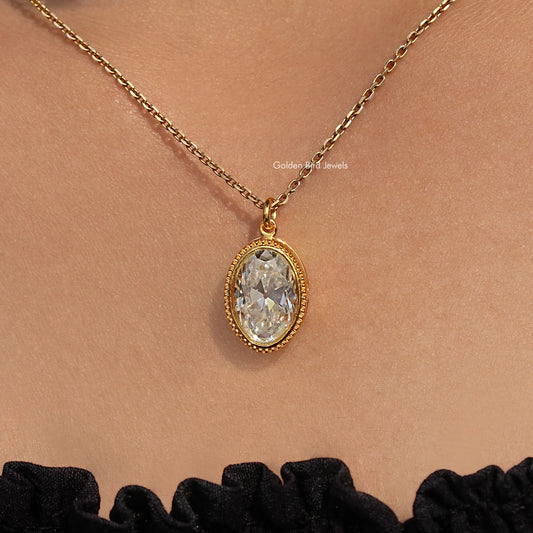 Gold-tone oval bezel pendant with bezel-set white stone hanging on chain