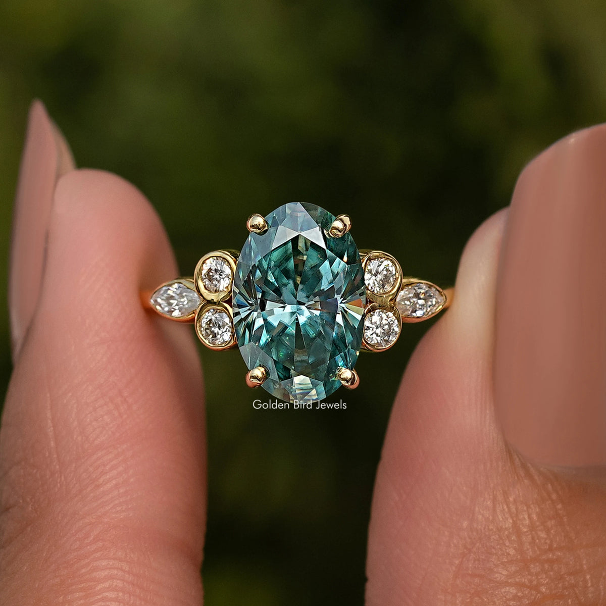 Close-up of oval blue-green moissanite proposal ring with round halo stones