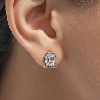 Cushion-cut diamond stud earring with milgrain bezel in gold setting on ear
