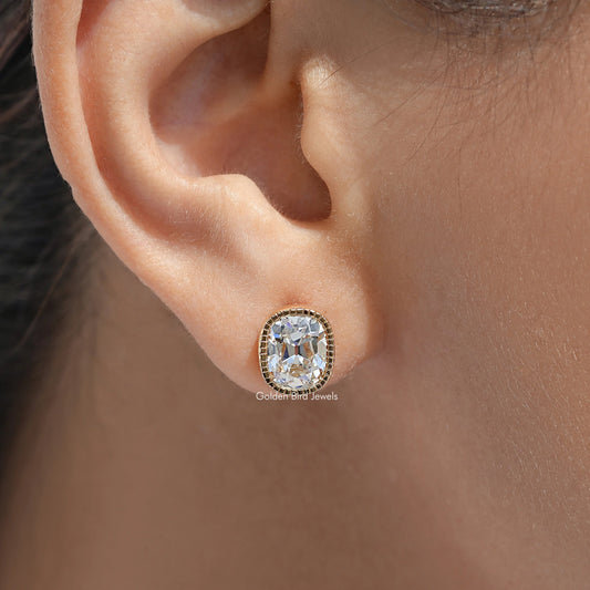 Cushion-cut diamond stud earring with milgrain bezel in gold setting on ear