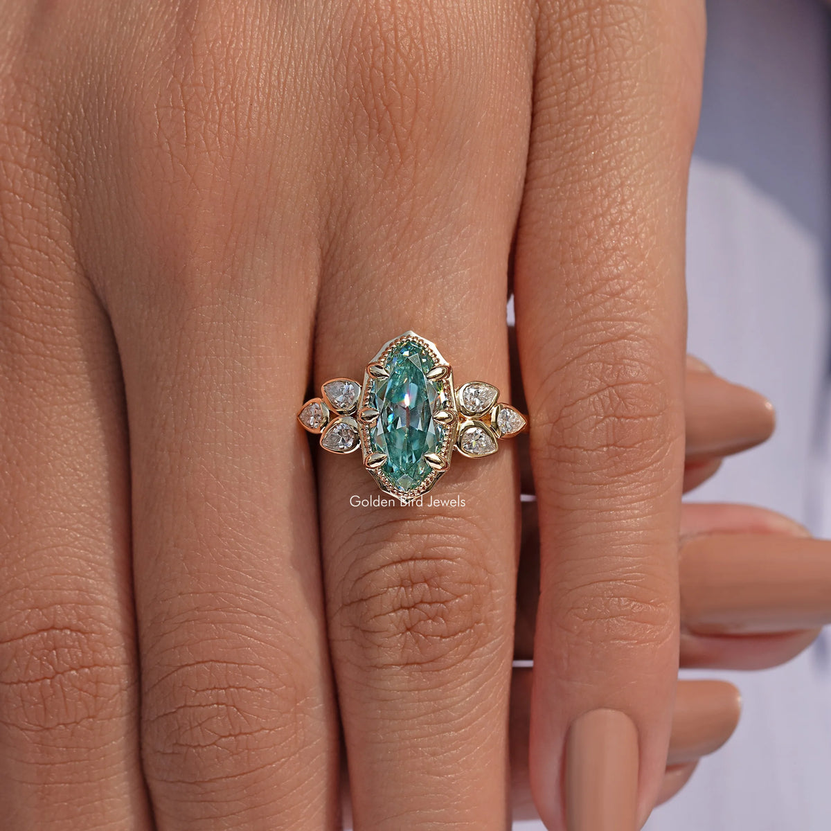 Blue oval moissanite ring with round halo stones on side, worn on hand