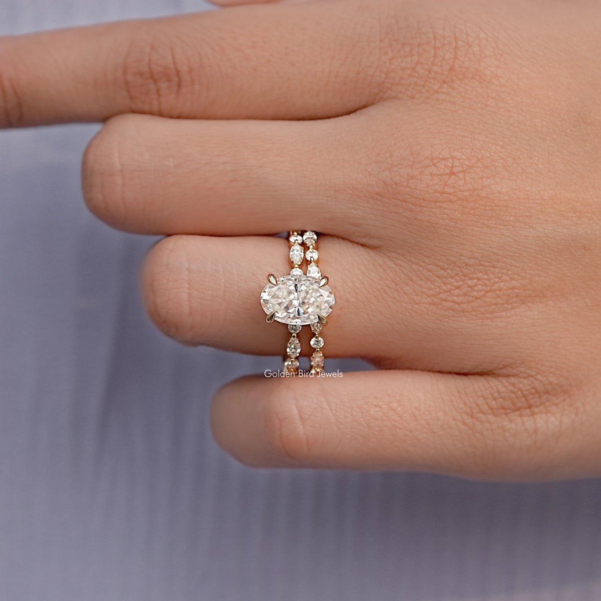 Oval moissanite bridal ring set with two slim pavé bands on a hand