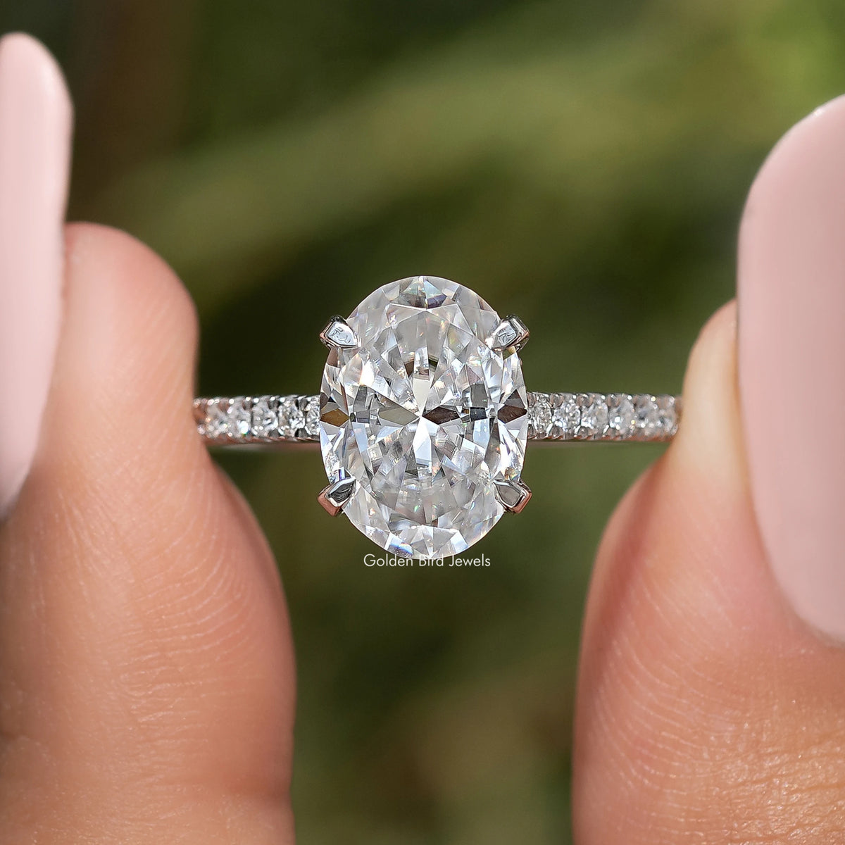 Close-up of oval-cut moissanite center stone, prong setting with pave band