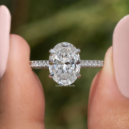 Close-up of oval-cut moissanite center stone, prong setting with pave band
