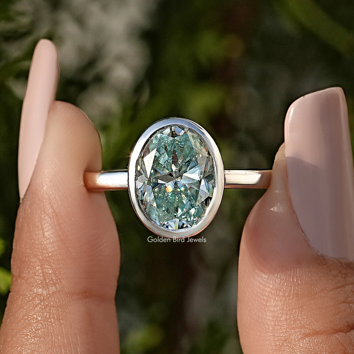 Oval moissanite bezel-set solitaire ring with metal band, close-up front