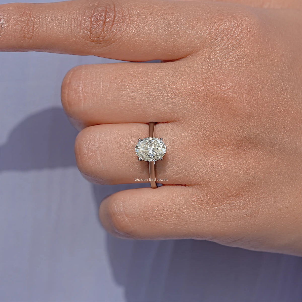 Oval moissanite solitaire ring with prong-set oval stone, silver band view