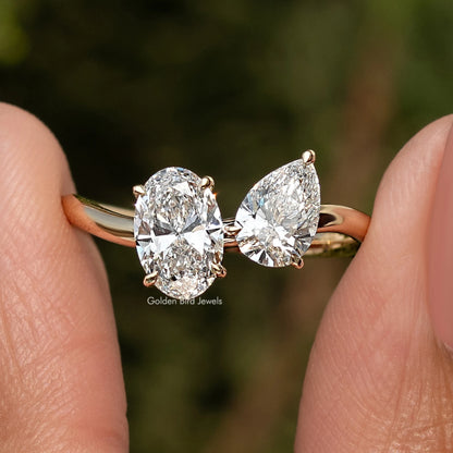 Gold toi et moi ring close-up showing oval and pear-cut lab diamonds with raised bezels