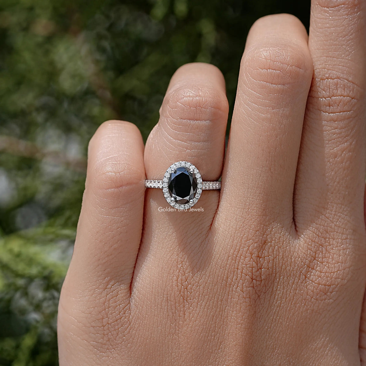 Oval black moissanite halo wedding ring in silver on a hand