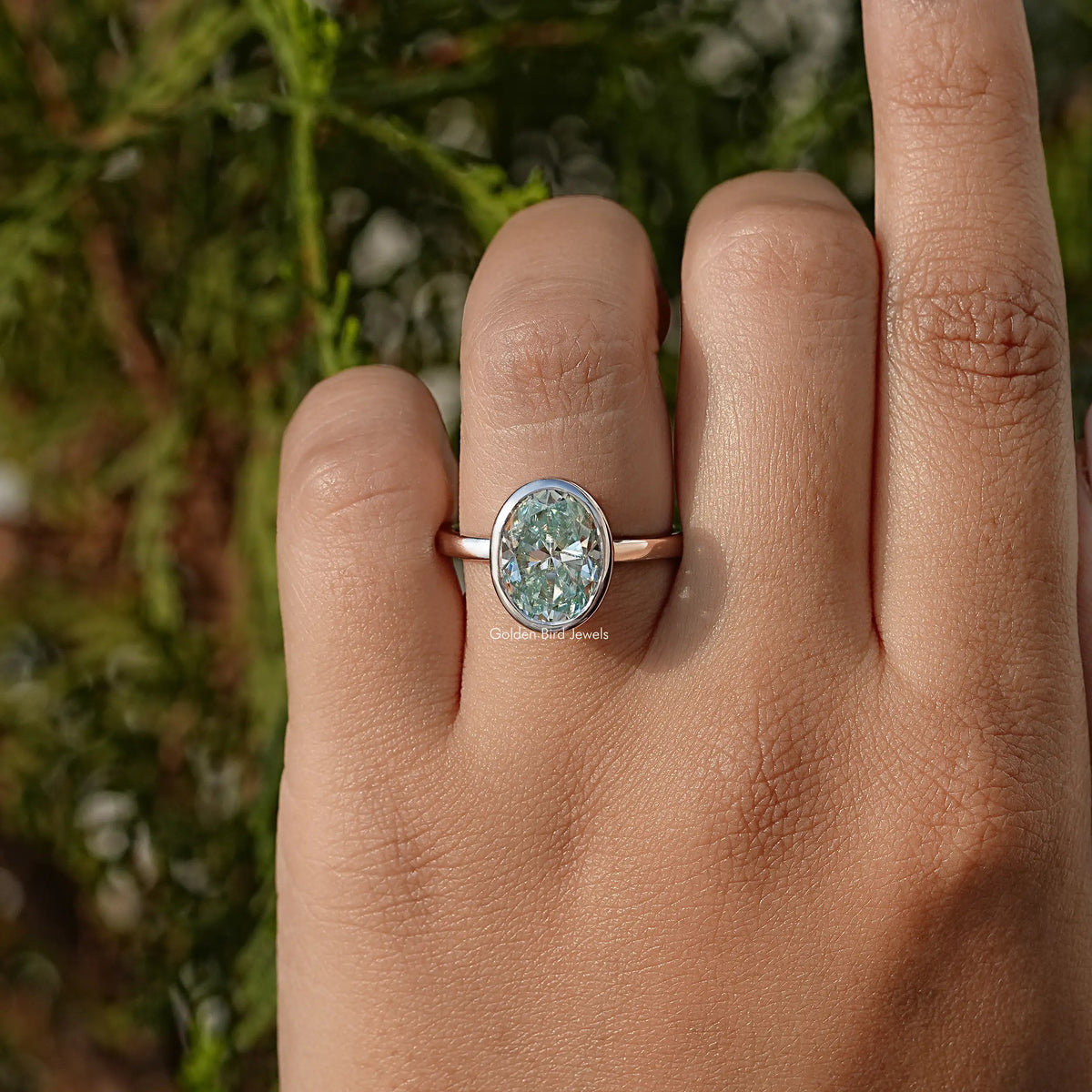 Rose-gold oval moissanite solitaire ring, bezel-set center stone on finger