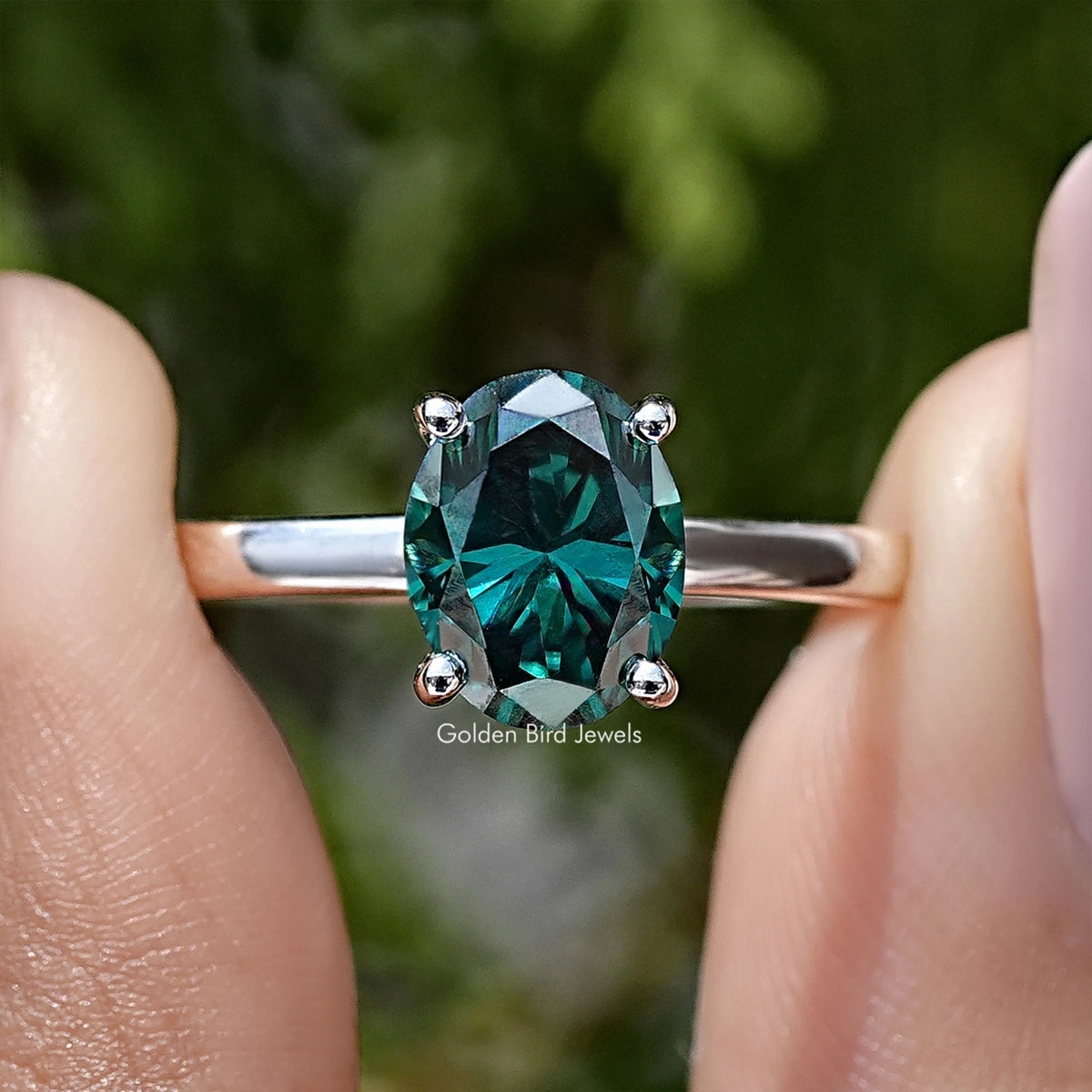 Oval-cut teal moissanite ring with sterling prongs, hidden halo detail front close-up