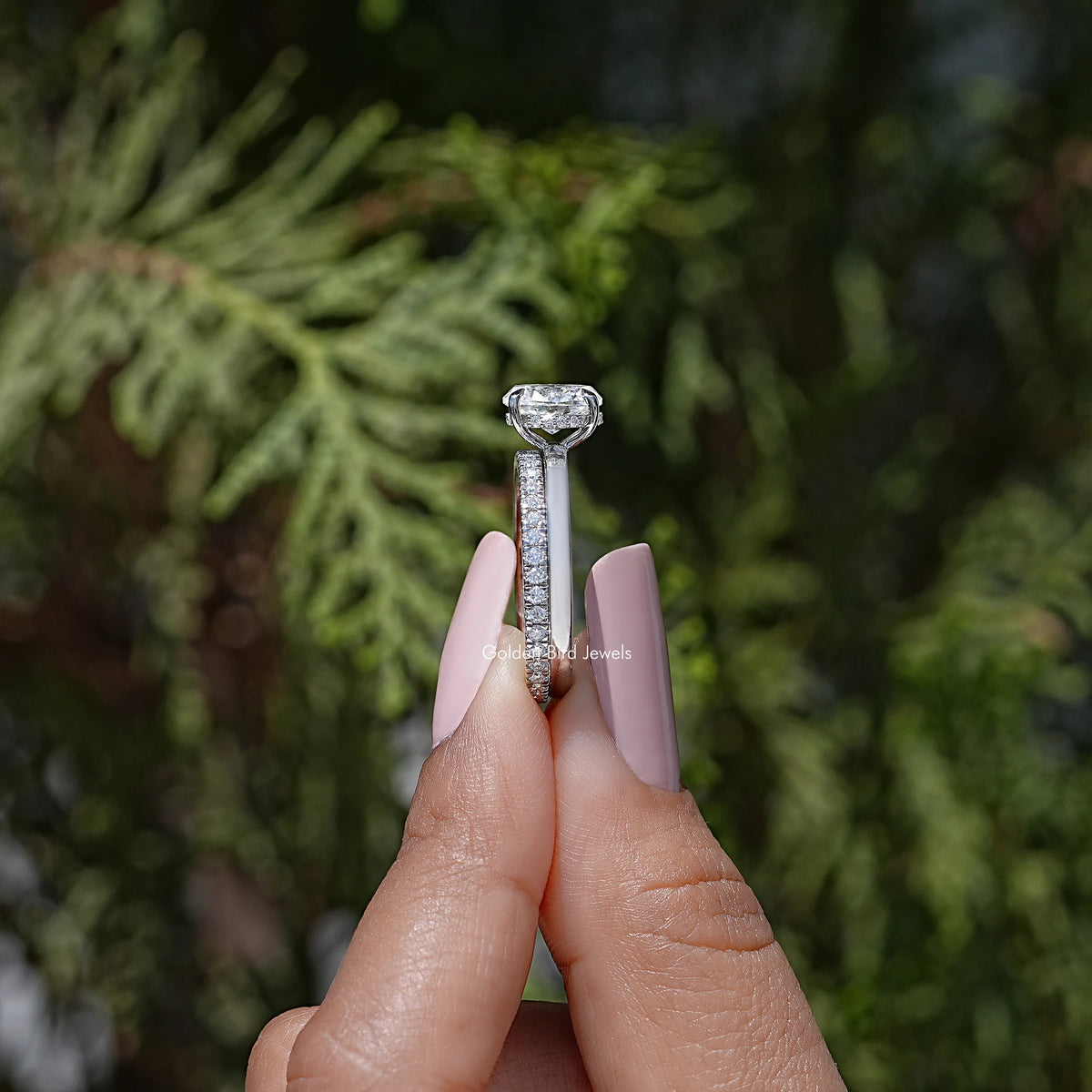 Oval moissanite ring with raised prongs, shown from the top on a fingertip