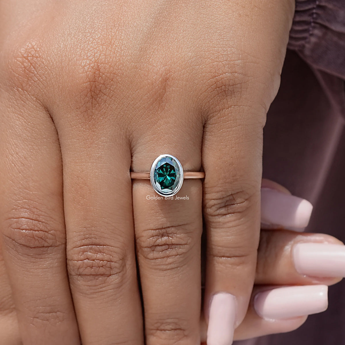 Oval teal moissanite solitaire ring, bezel setting in sterling silver on hand