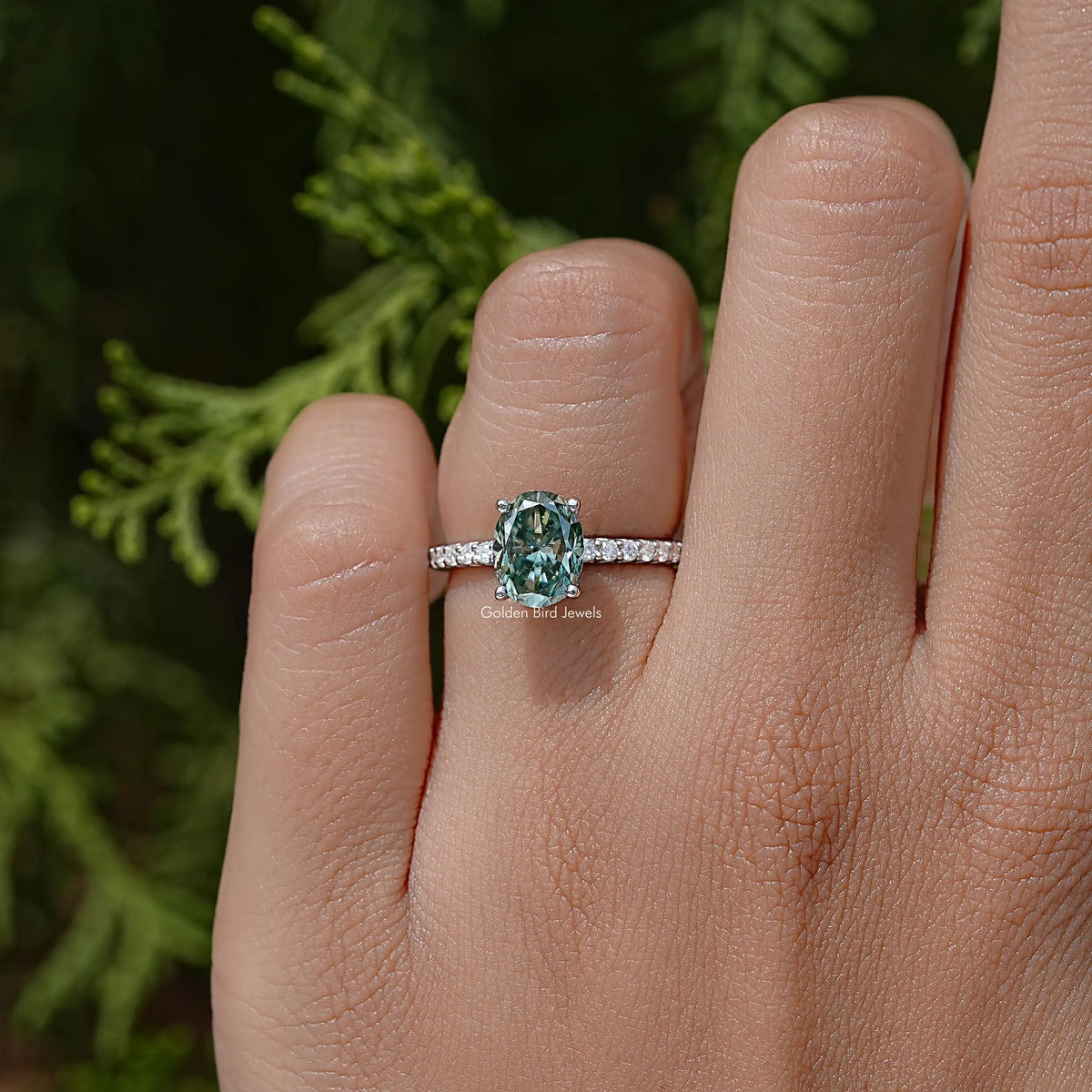 Teal oval moissanite solitaire on 925 silver band with small clear stone accents