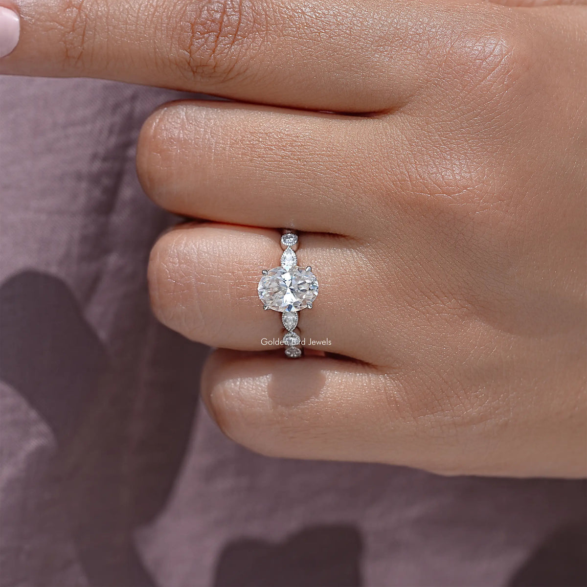 Oval moissanite ring on finger, sterling silver band with small round side stones
