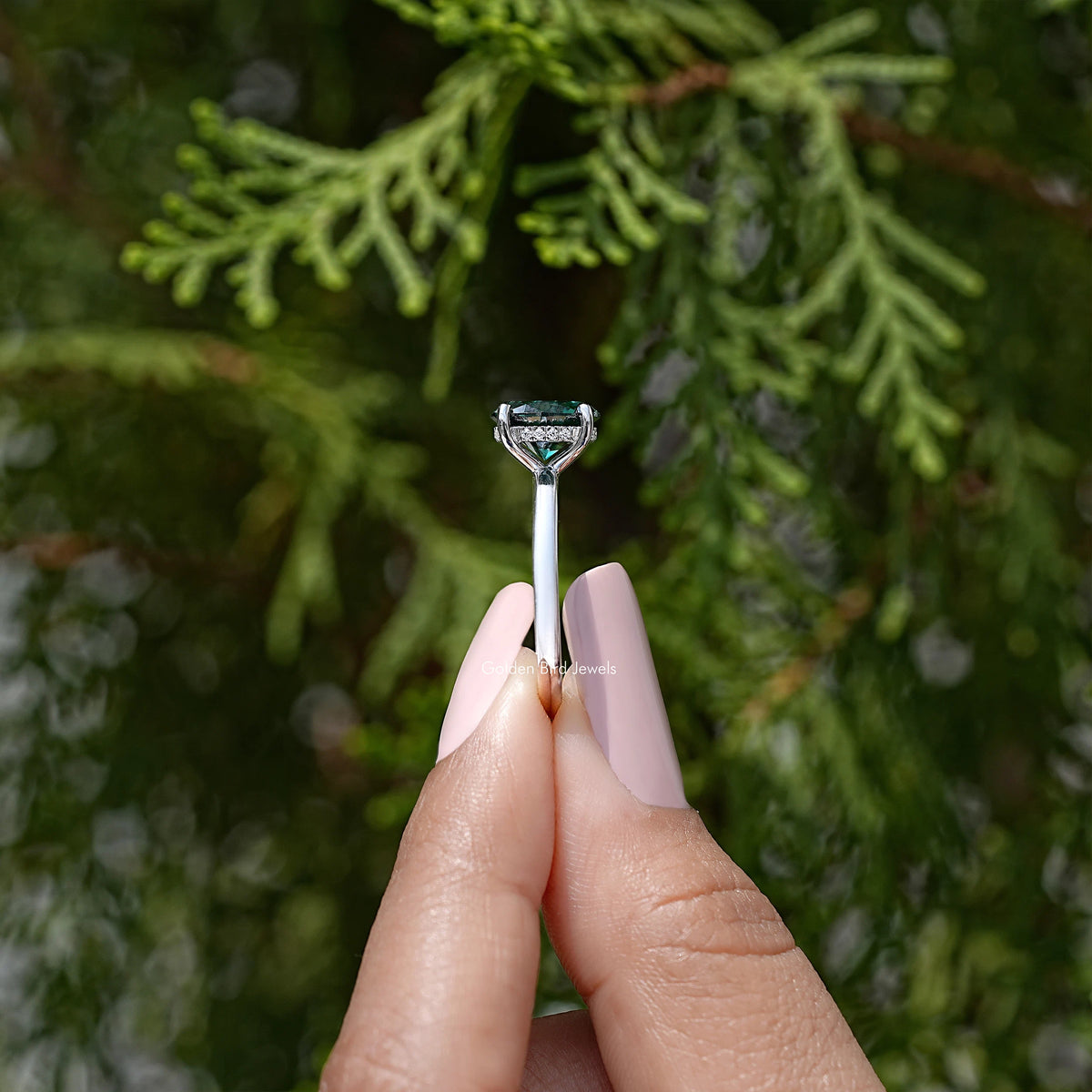 Oval-cut moissanite engagement ring with teal center stone, prong setting side view