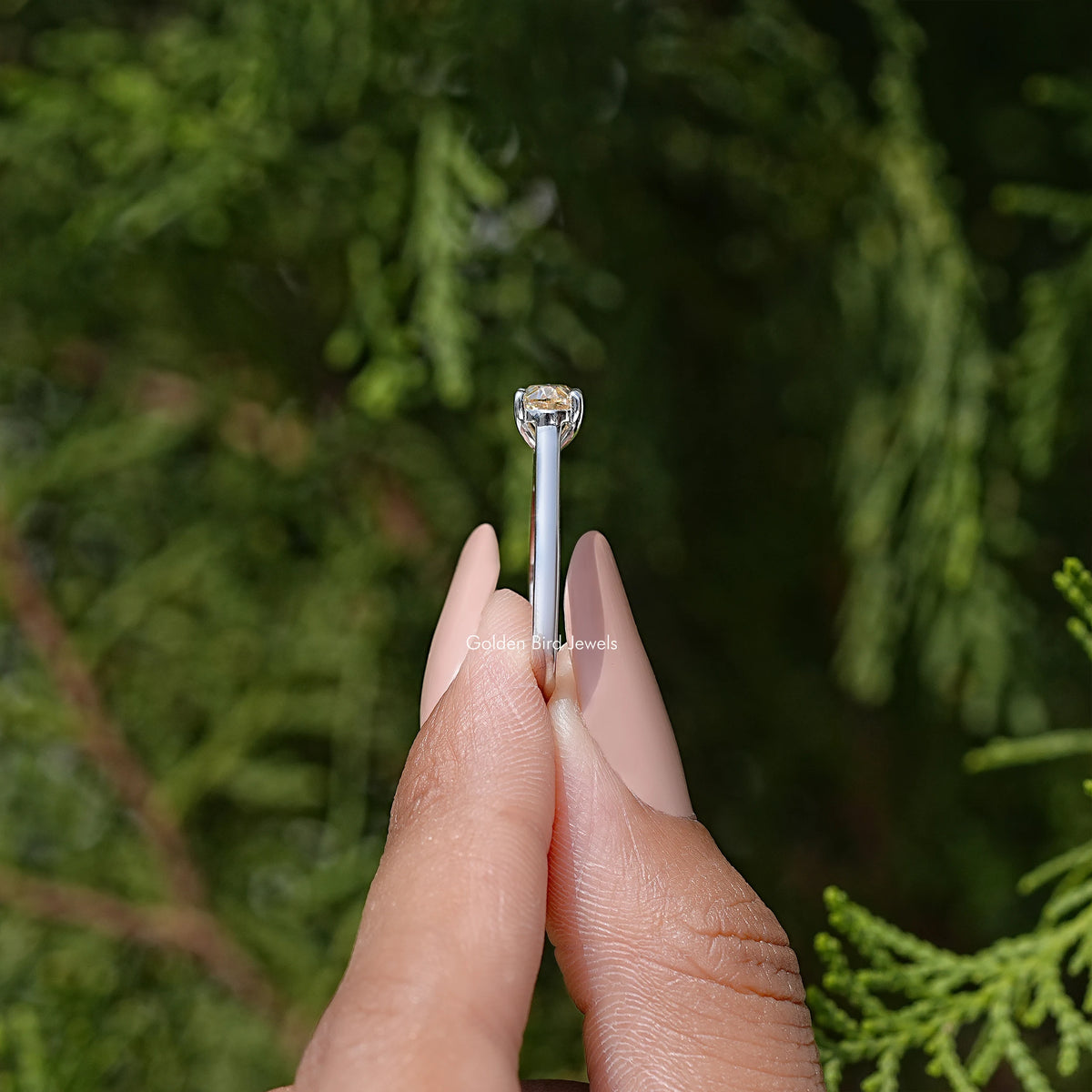 Oval cut moissanite solitaire ring with four-prong head, side view.
