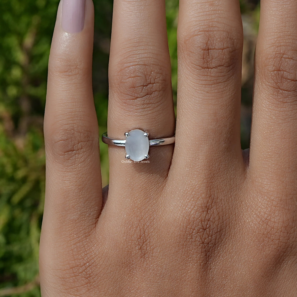 Oval moonstone solitaire ring with silver setting and light blue oval center gem