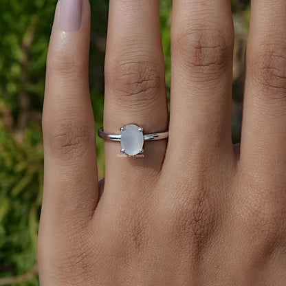 Oval moonstone solitaire ring with silver setting and light blue oval center gem
