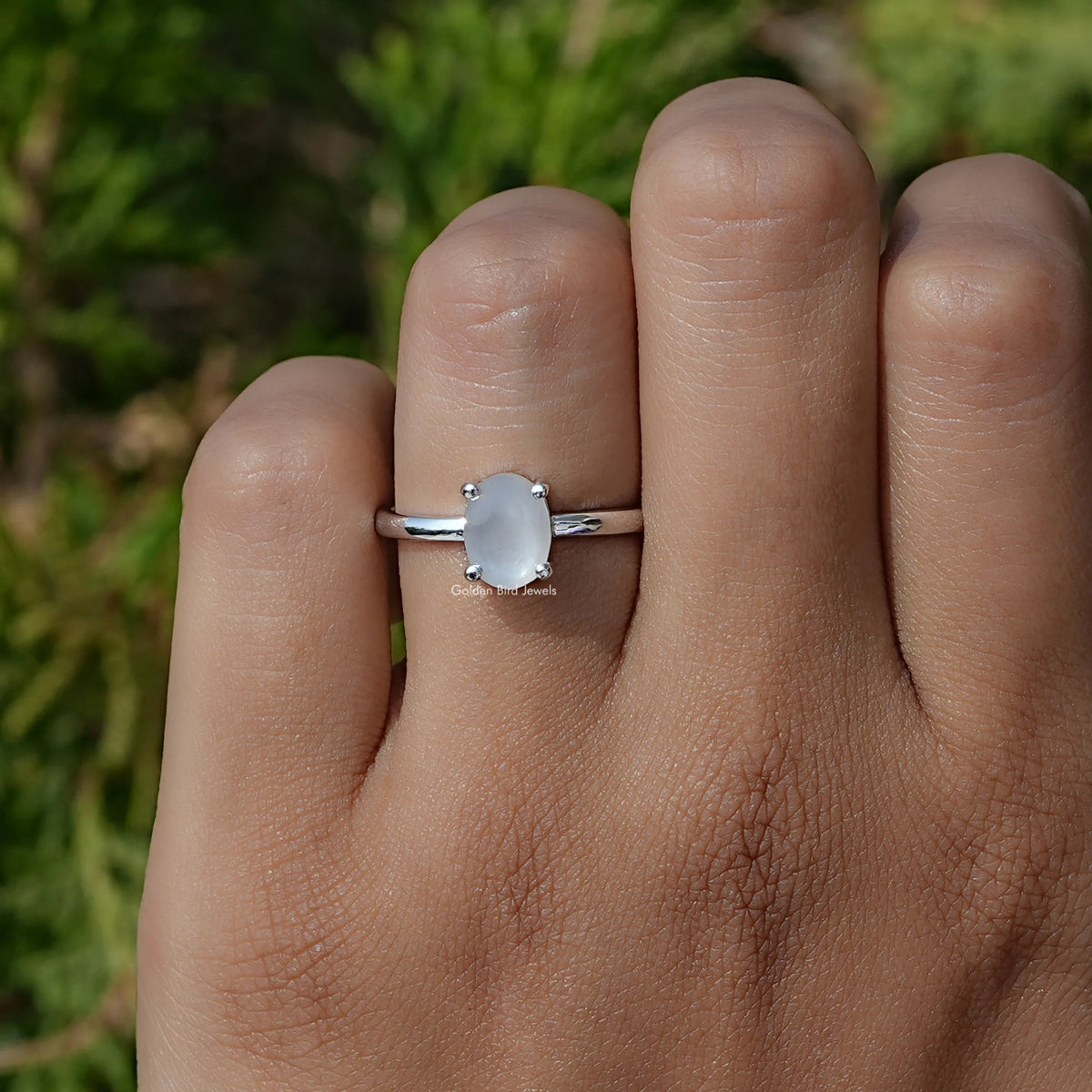 Oval moonstone solitaire ring in silver with small side prongs and slim band