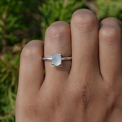 Oval moonstone solitaire ring in silver with small side prongs and slim band