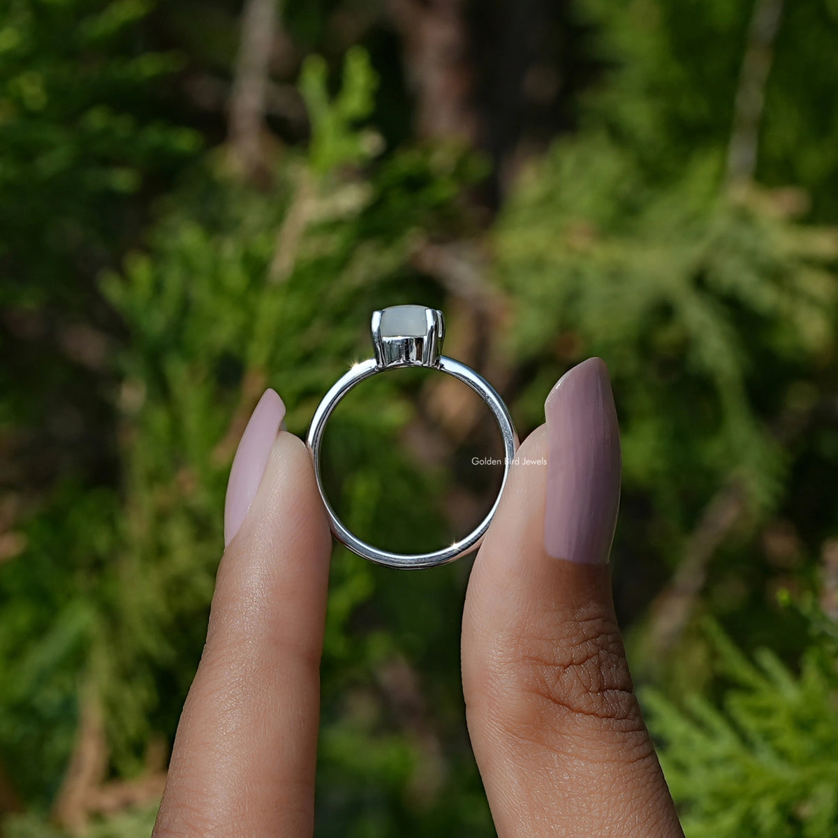 Silver oval moonstone solitaire ring viewed from front; pronged head and band