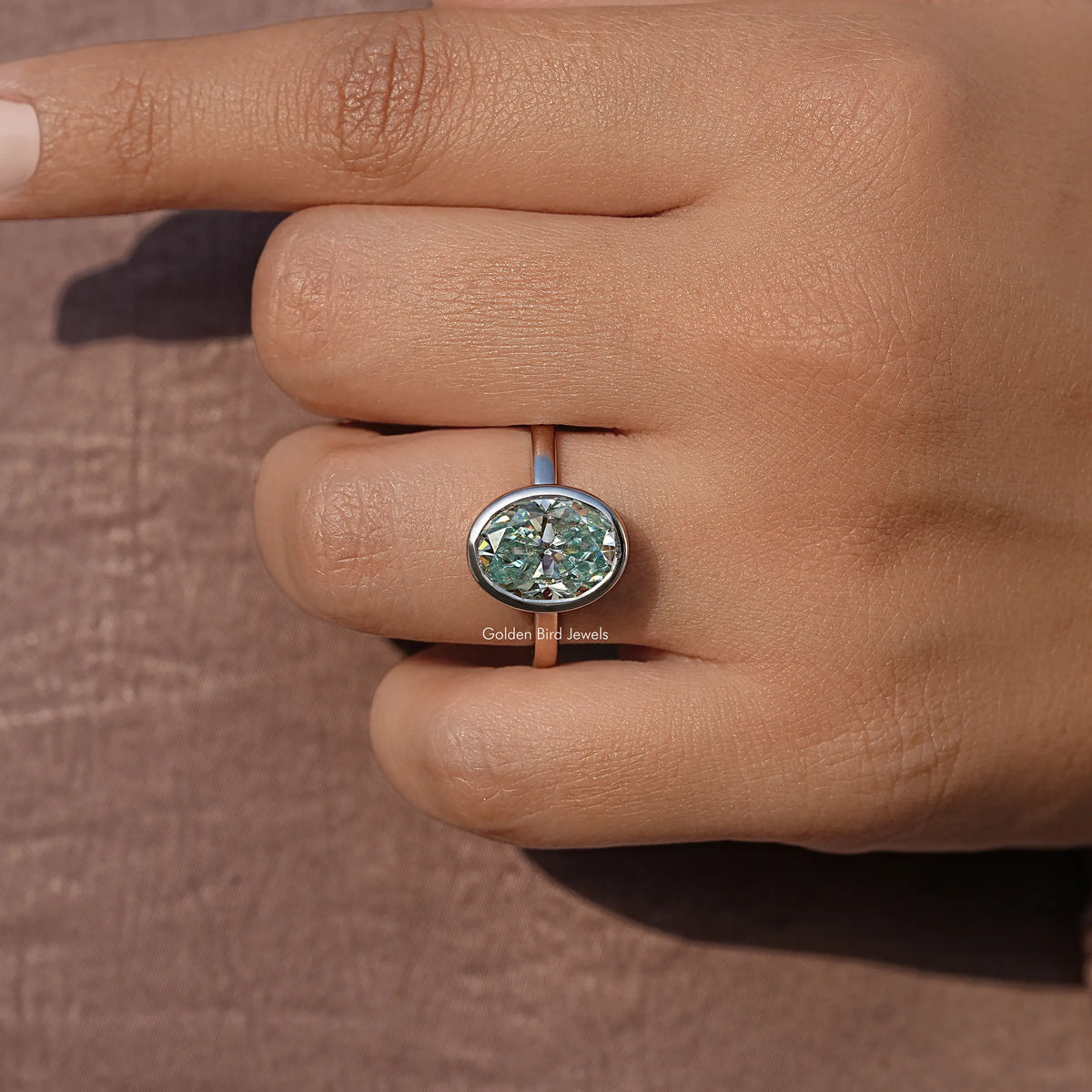 Oval moissanite bezel-set solitaire ring close-up on finger