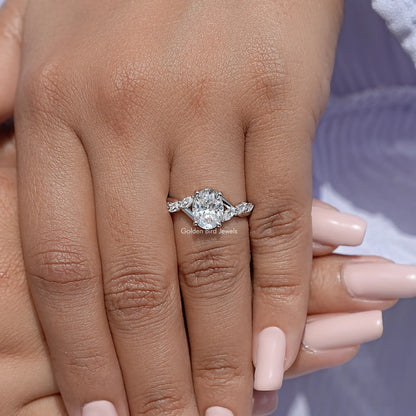 Oval moissanite solitaire ring on hand, floral side stones, sterling silver band
