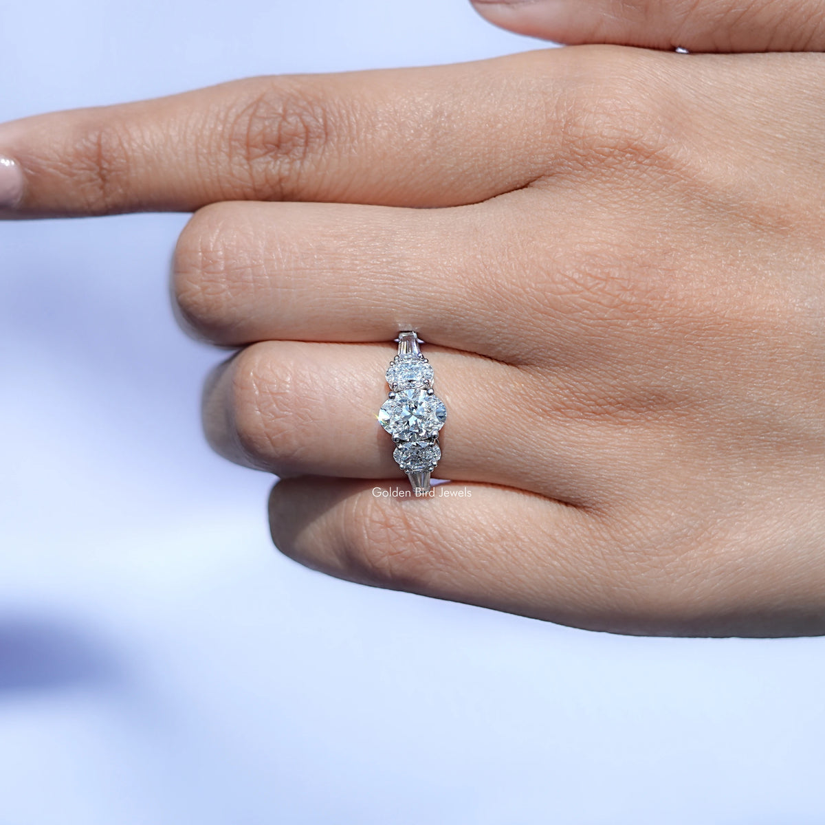 In finger front view of Oval And Tapered Baguette Cut Lab Diamond Five Stone Ring In White Gold