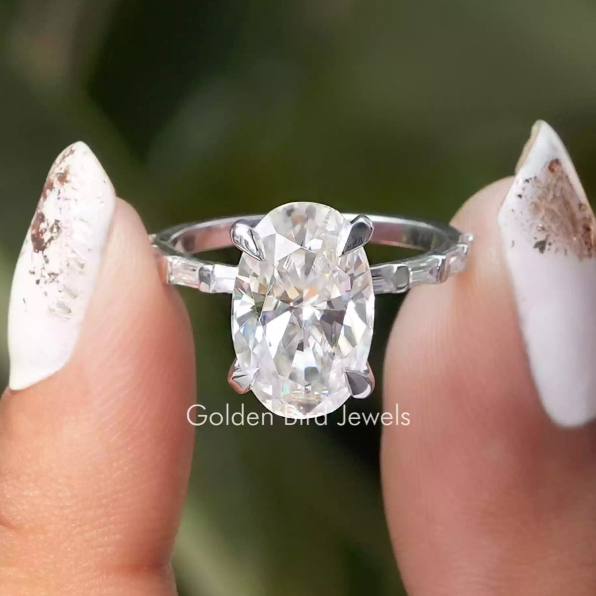 Front view of Crushed Ice Oval And Baguette Cut Moissanite Accent Set Ring  in two fingers 