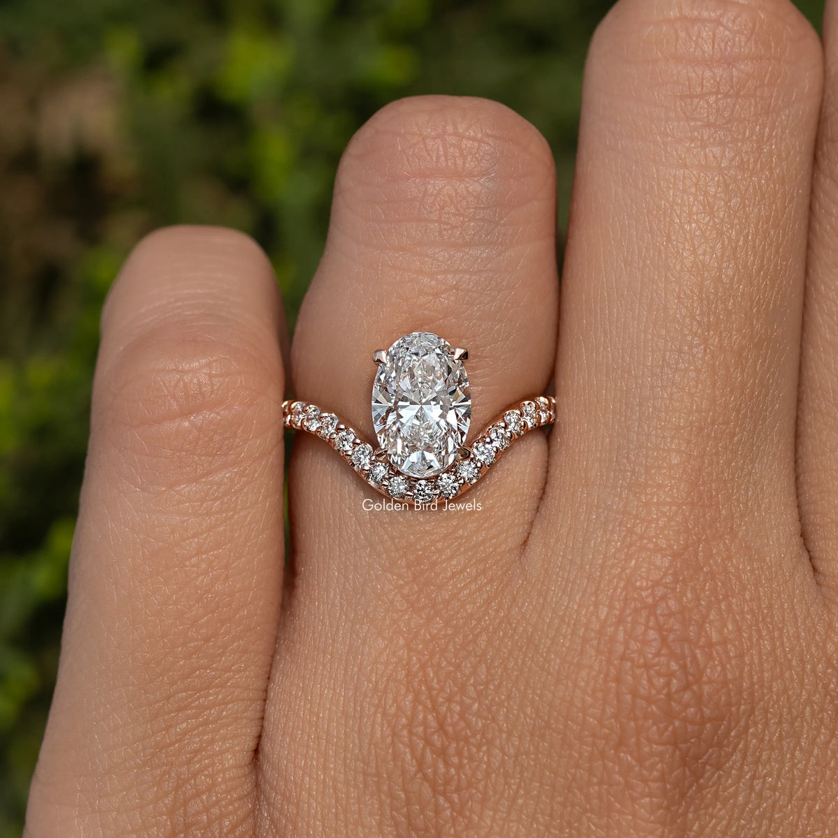 Oval cut diamond ring with curved pavé accent band on a finger