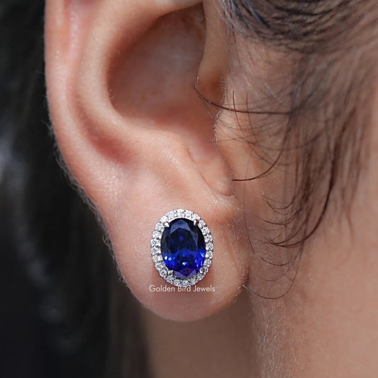 Close-up of an ear wearing a blue gemstone earring with a blurred background