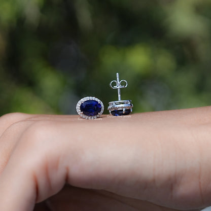 Sapphire earrings on a hand with a blurred green background