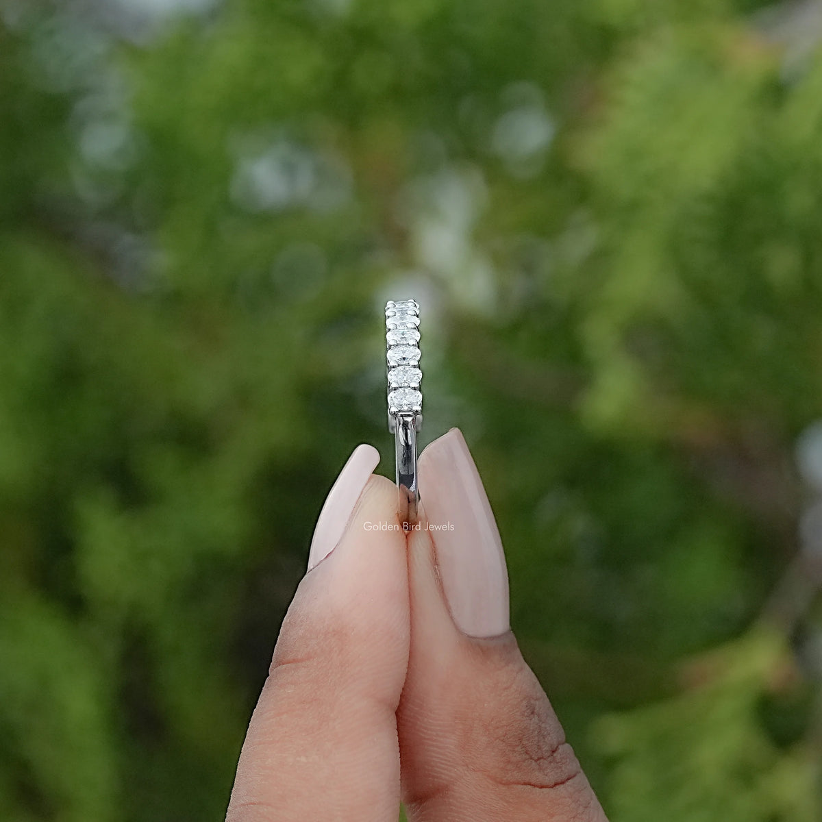 Sterling silver half-eternity ring with oval moissanite stones, side view on finger