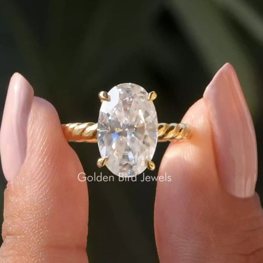 Oval-cut moissanite solitaire ring with gold-tone band and 4-prong setting