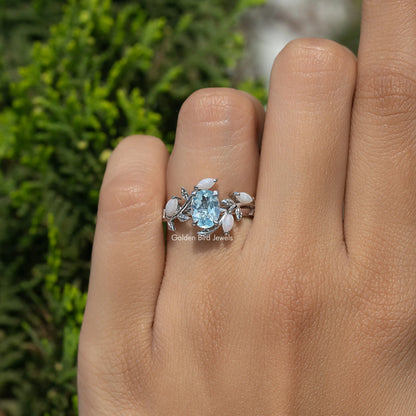 Argentium silver oval blue gemstone bypass ring with small leaf accents on hand