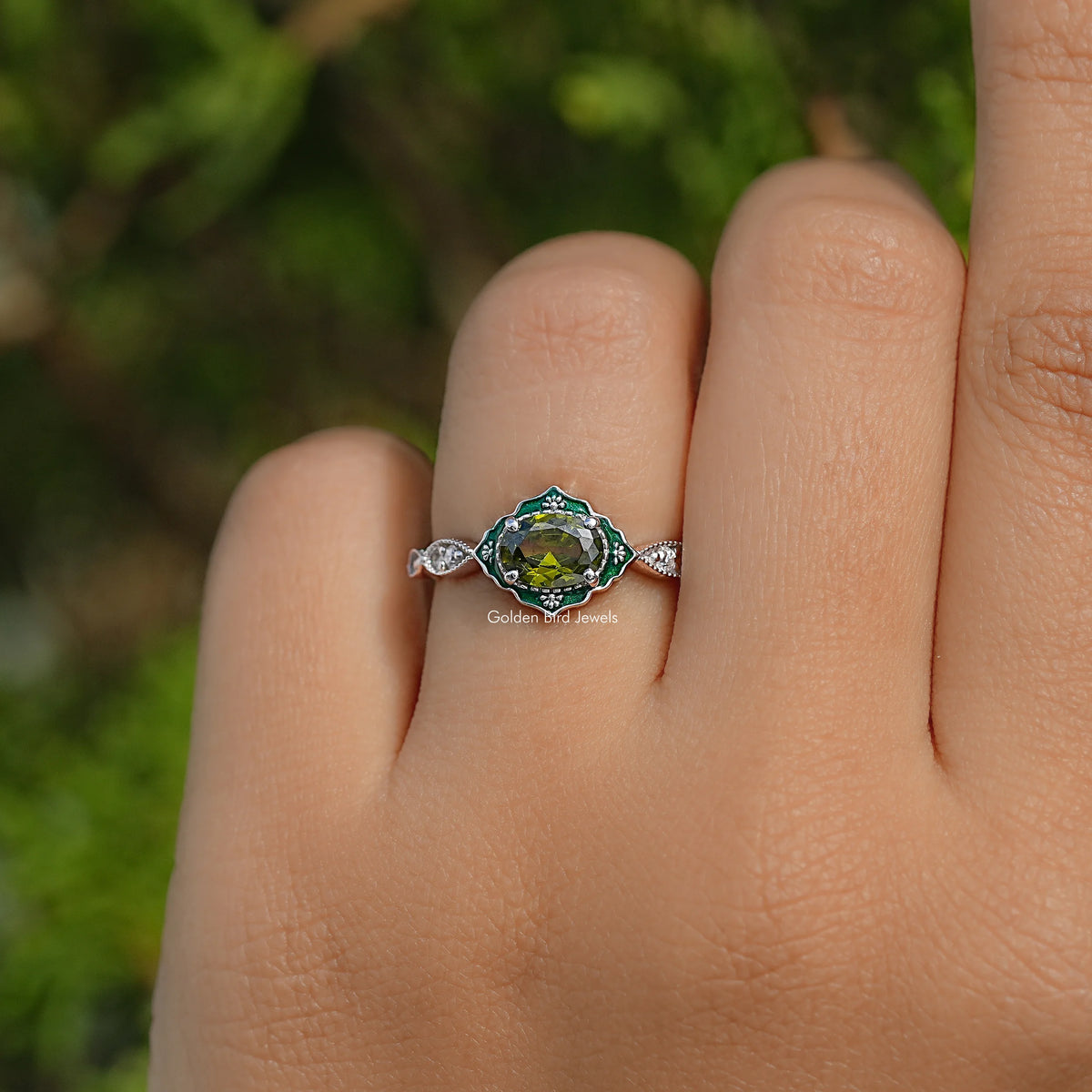 Oval green center gemstone with diamond halo engagement ring on open palm