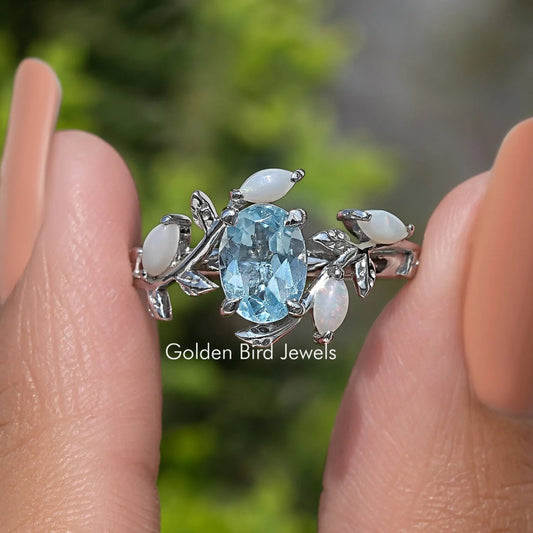 Argentium silver bypass ring with oval blue gemstone and leaf-style accents
