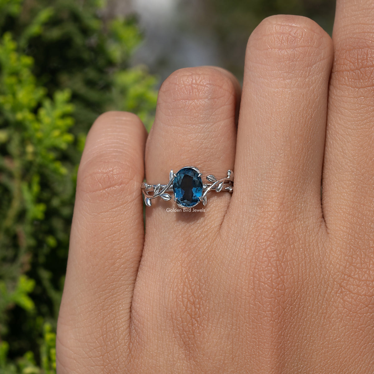 Blue oval gemstone ring with leaf motifs, slim Argentium silver band