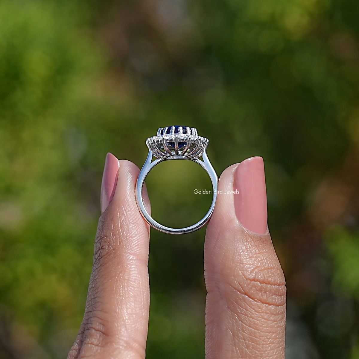 Sterling silver open side view of oval halo engagement ring with blue center