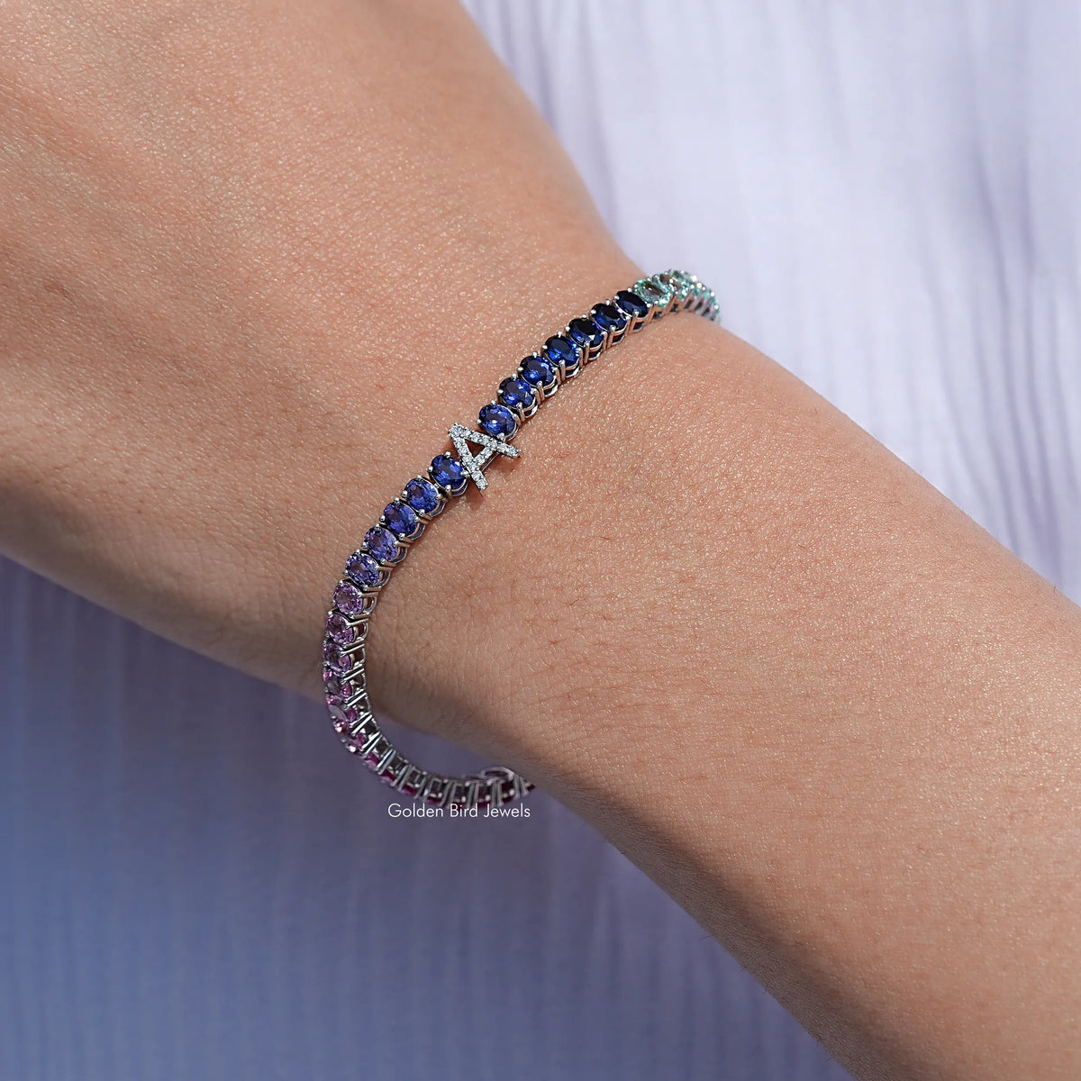 Blue oval gemstone tennis bracelet with subtle green and purple stone accents