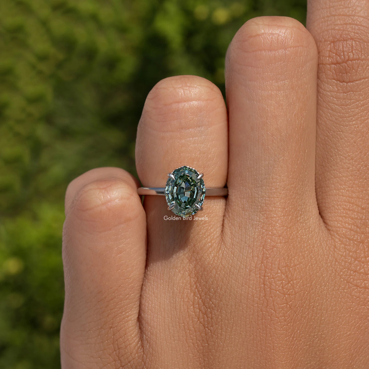Sterling silver solitaire ring, side view of oval teal step-cut center stone