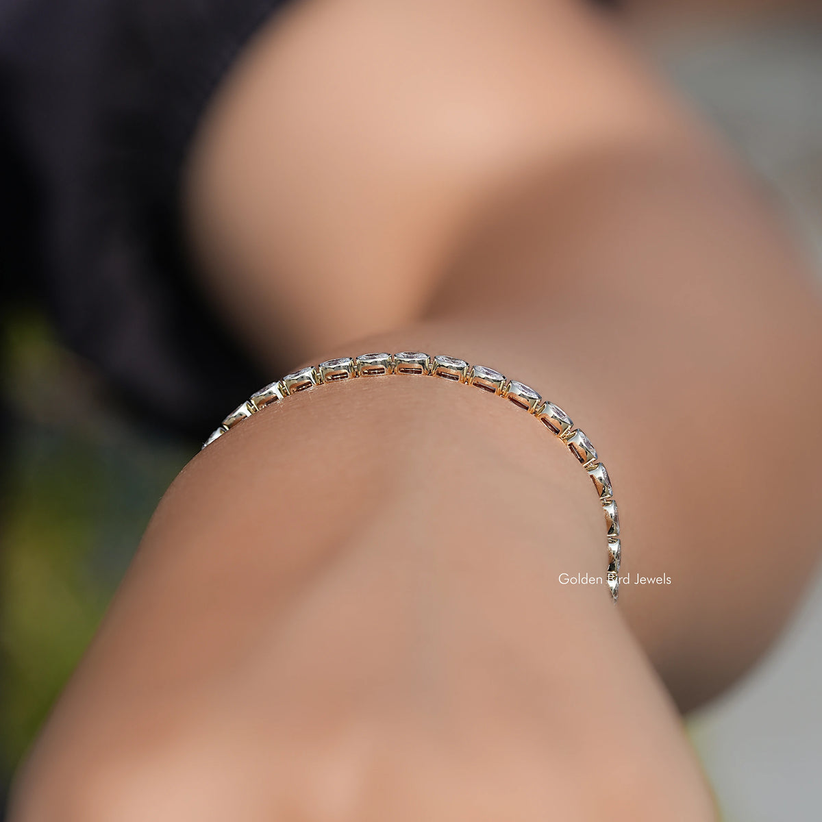Silver-tone oval diamond tennis bracelet close-up, stone-studded top row on wrist